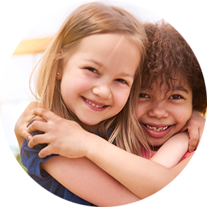 Two smiling children hugging each other