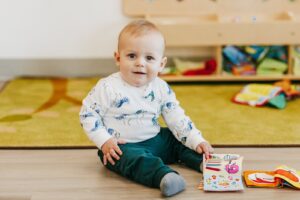 Infant child sitting on floor with soft book