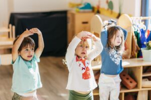 Three children holding arms over their heads in a circle