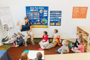 Teacher in classroom setting teaching children sitting on floor