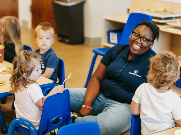 Teacher sitting on floor smiling at children