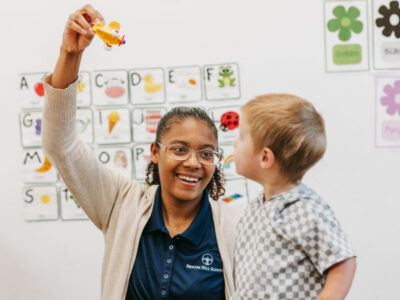 Woman holding toy in air with child looking at toy
