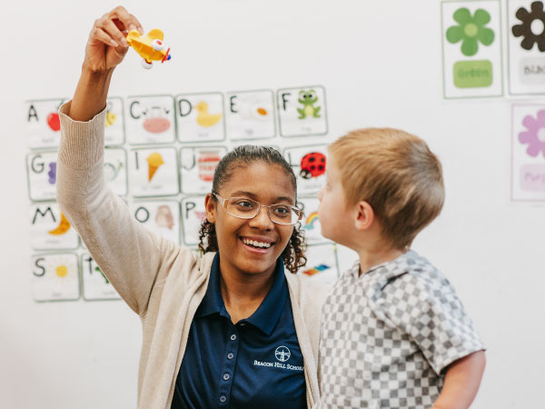 Woman holding toy in air with child looking at toy