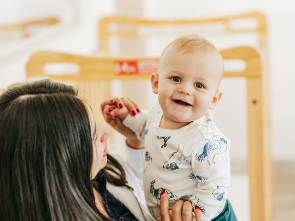 Caregiver holding smiling infant on lap