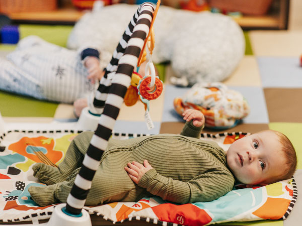 Infant laying on mat with hanging toys