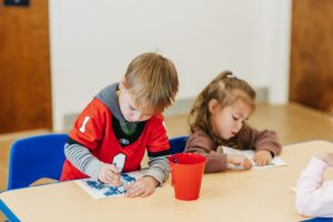 Two children working on art at a table