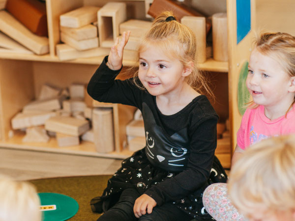 Girl sitting on floor with hand raised
