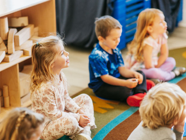Children sitting on floor listening intently to teacher
