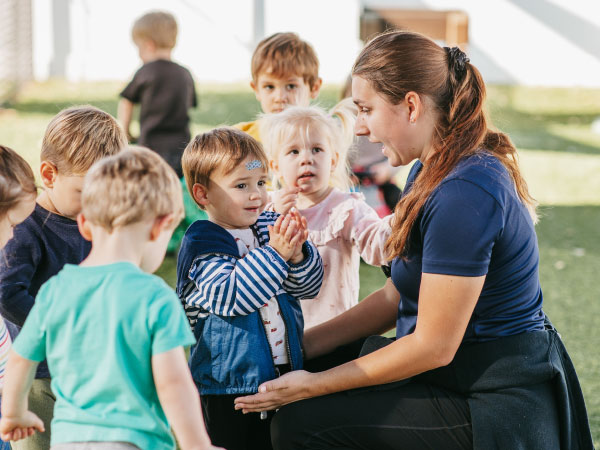 Caregiver squatting down in front of small children