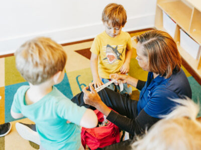 Teacher sitting on floor with children working on project