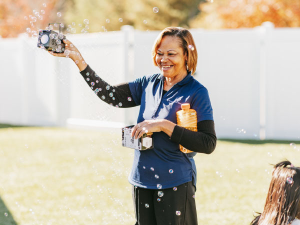 Caregiver blowing bubbles outside in yard