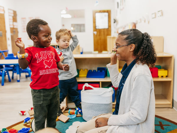 Teacher sitting on floor working two toddler children