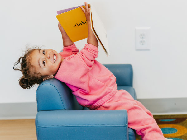 Two year old girls in blue chair looking at book