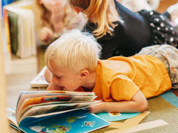 Young child laying on floor looking at book